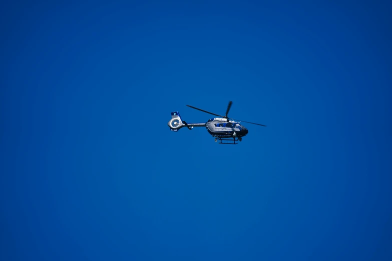 a small helicopter flying high in the blue sky