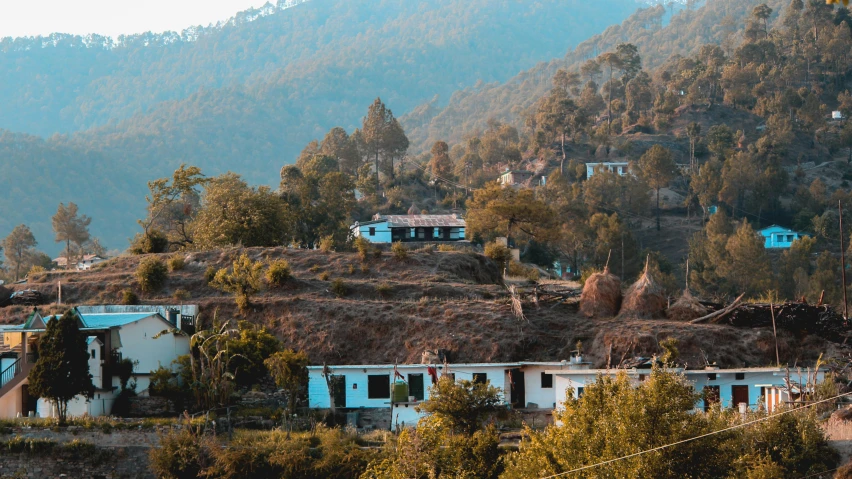 a view of a hillside with houses and green mountains in the background