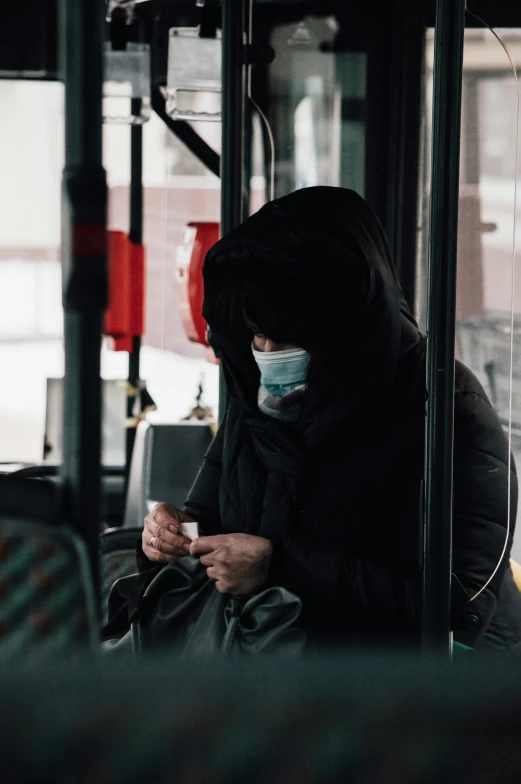 woman wearing mask using cellphone in public bus