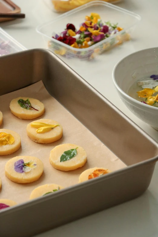 several yellow cookies in a pan with edible flowers on them