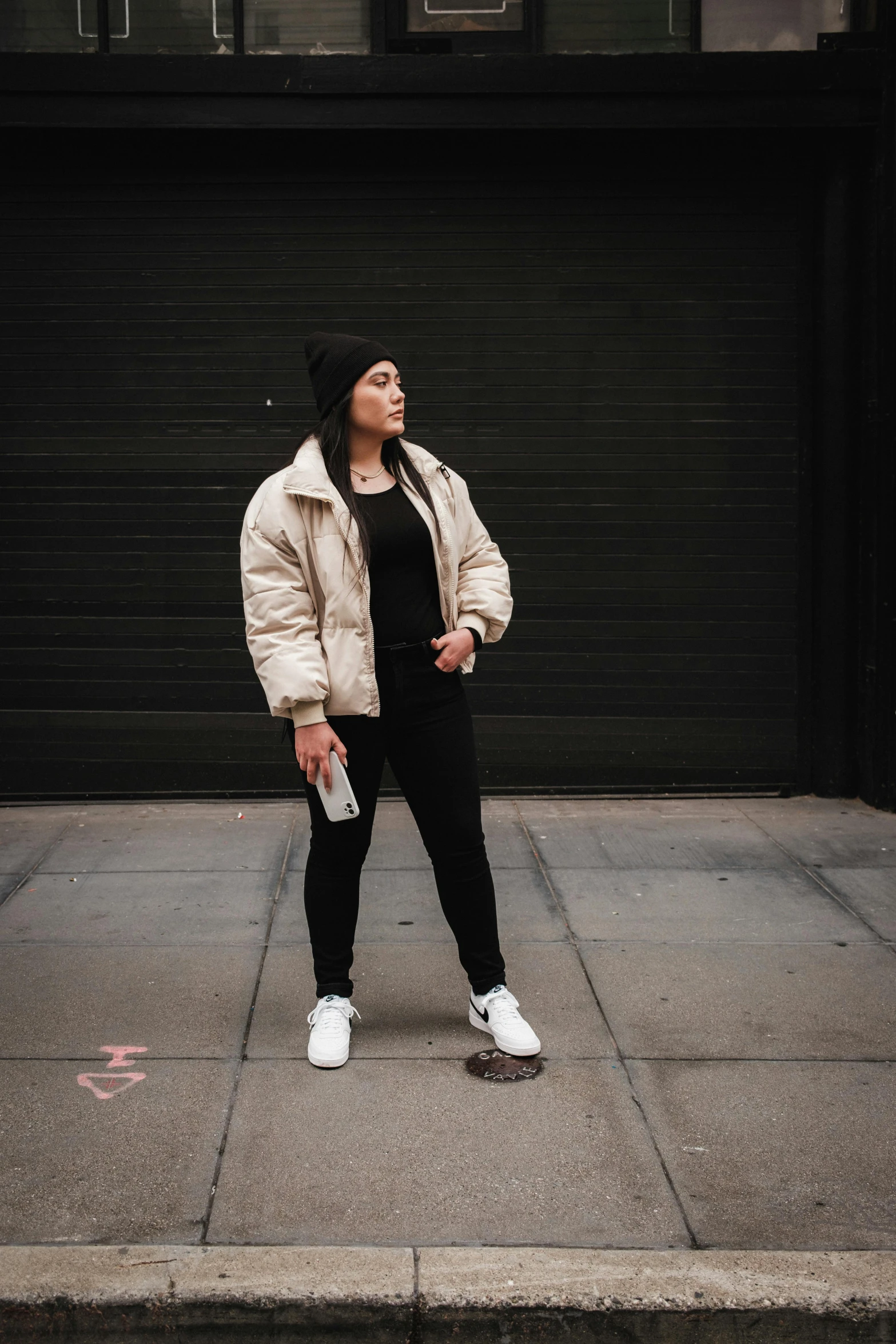 a woman standing on a city street in front of a garage