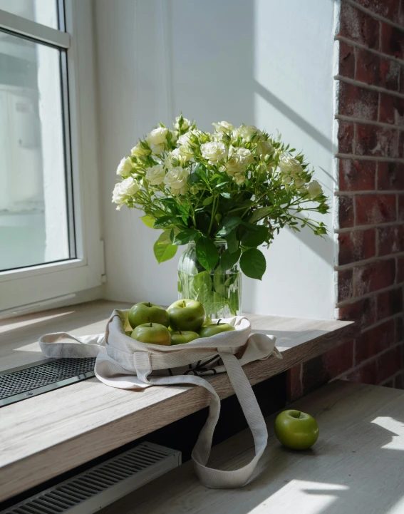 a vase filled with white flowers and green apples