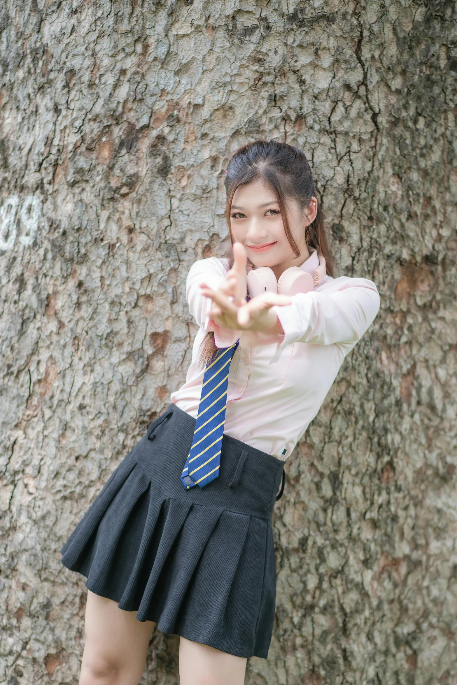 a young woman standing next to a tree in a skirt