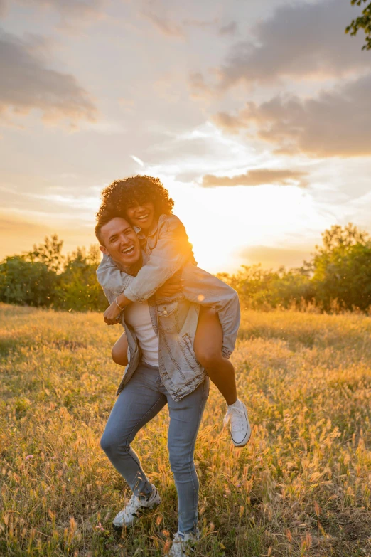 a guy in jeans carries his friend for a back - drop hug