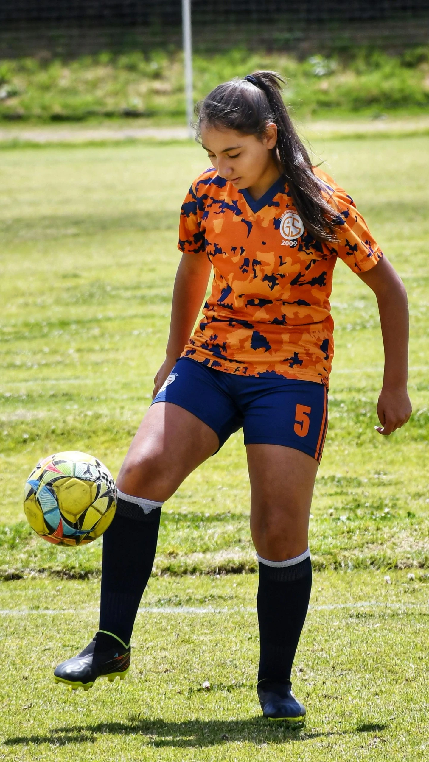 in an orange shirt kicking a soccer ball