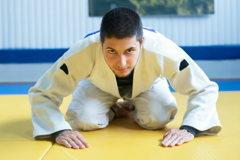 a man in white jacket on yellow wrestling mat