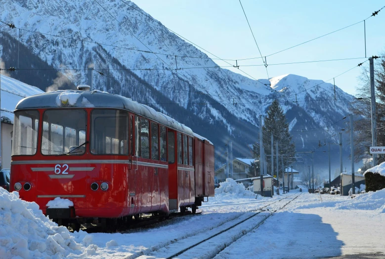 a red train traveling past a snow covered mountains