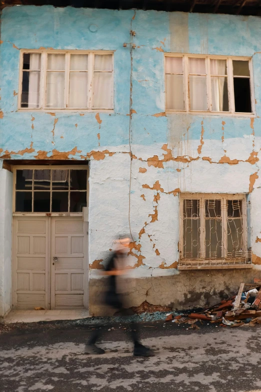 an image of man walking in front of a run down building