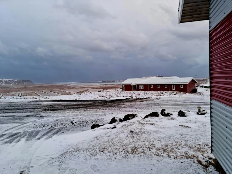 a farm and barn in the snow by some rocks
