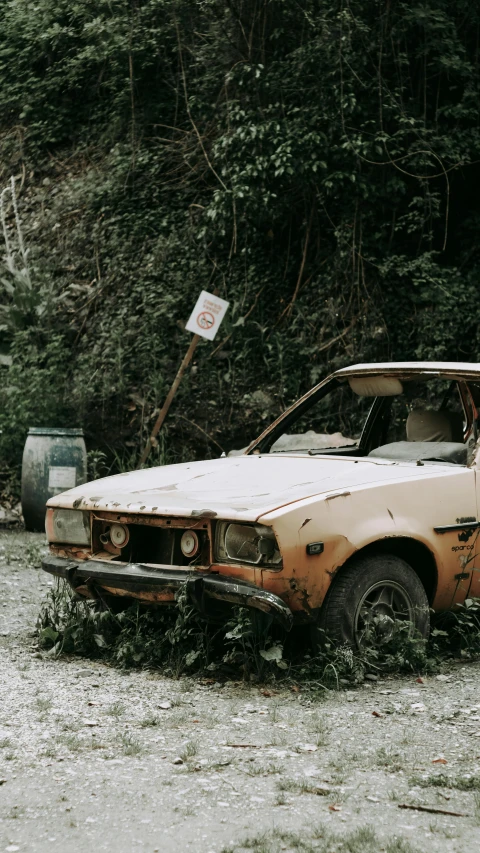 an abandoned dirty old car parked on the side of the road