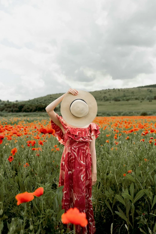 a woman with a straw hat standing in a field of flowers