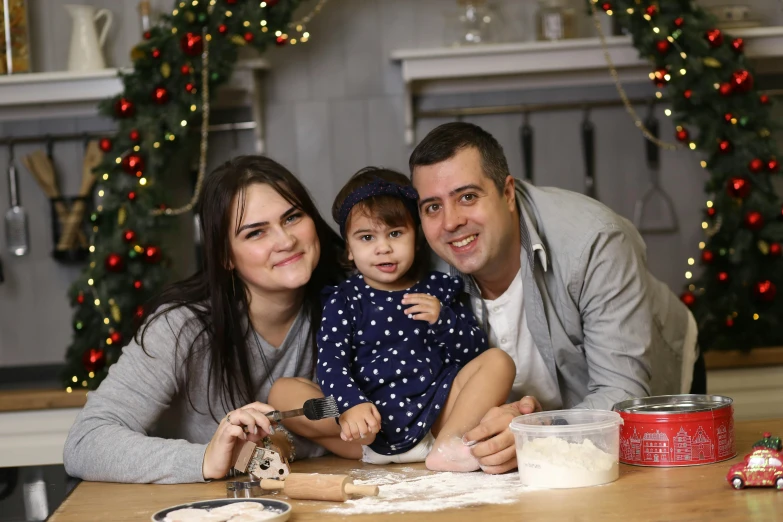 a couple and their young daughter pose for a picture with christmas decorations in the background