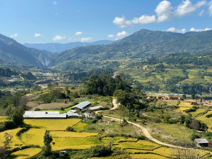 green hills and mountains under blue skies with clouds