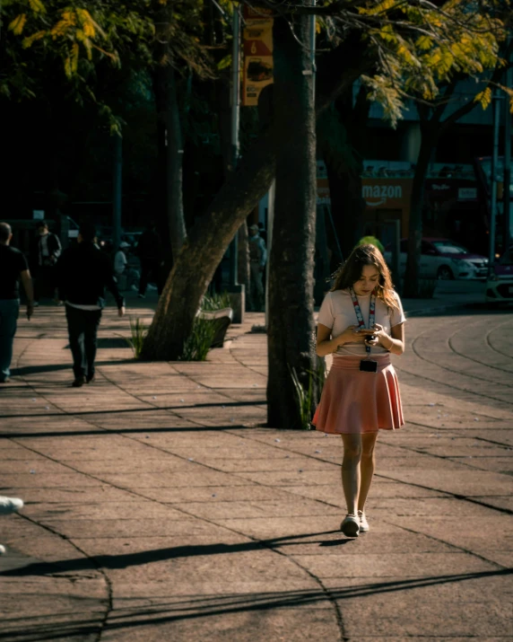 a woman walks on the side walk with a cell phone