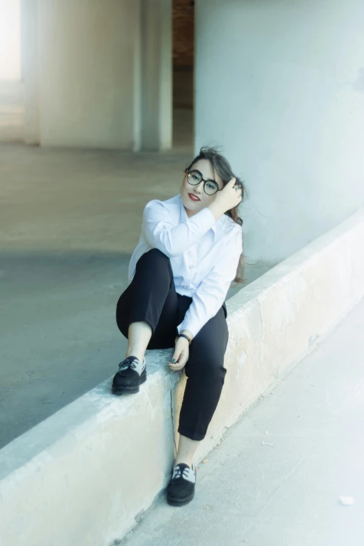 an attractive young woman sitting on top of a wall