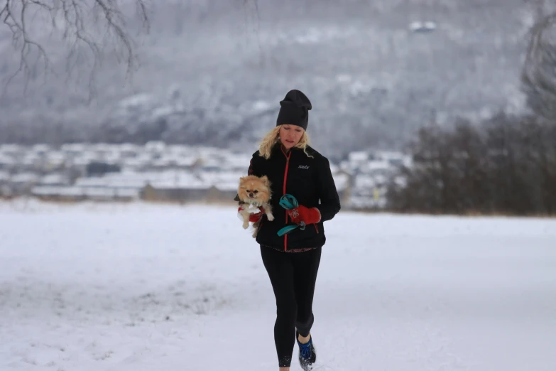 a woman walking in snow holding her dog