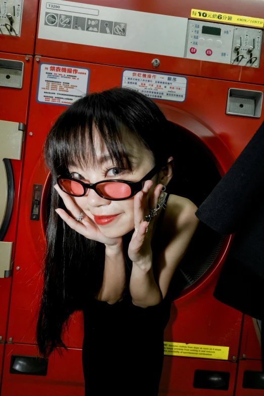 a girl wearing black sunglasses sitting by a machine