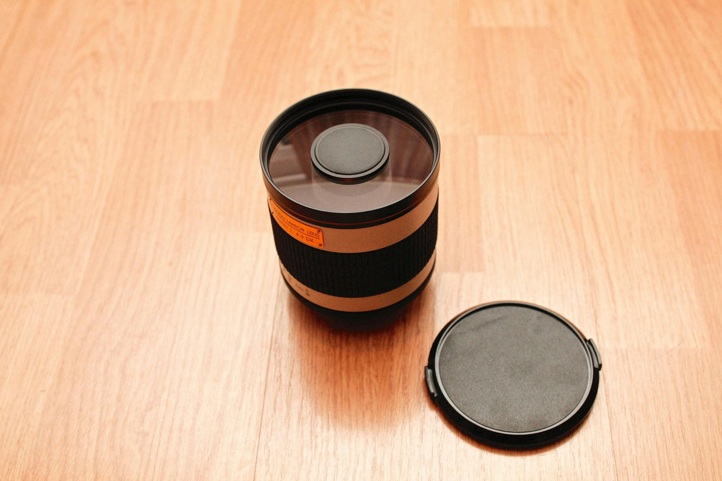 a bottle of alcohol sitting next to a can on a wood floor