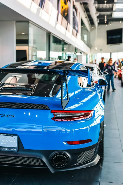 a blue sports car is parked in front of some people