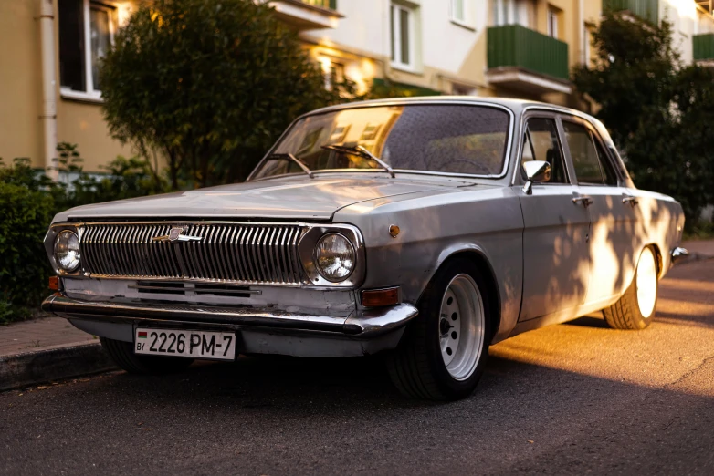 an old grey sedan parked on a side walk