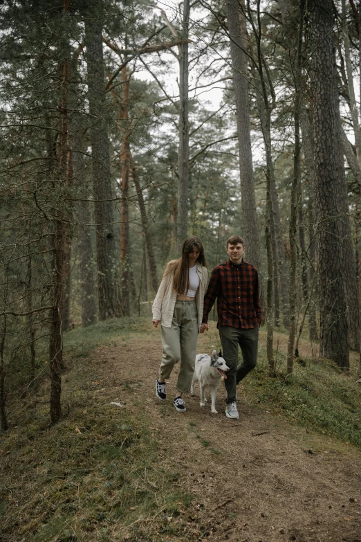 a couple is walking through the woods with their dog