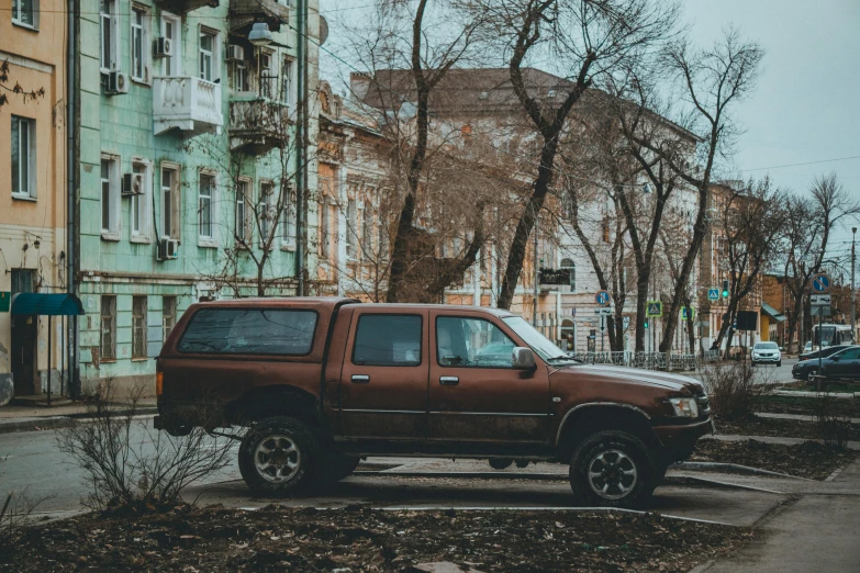 a small brown truck is parked next to the street