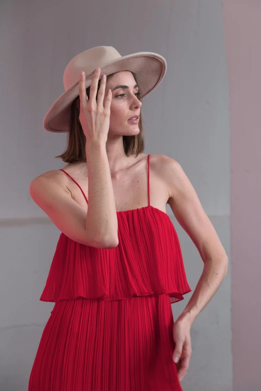 a model wears an outfit made with pleated fabric and wearing a wide brimmed straw hat