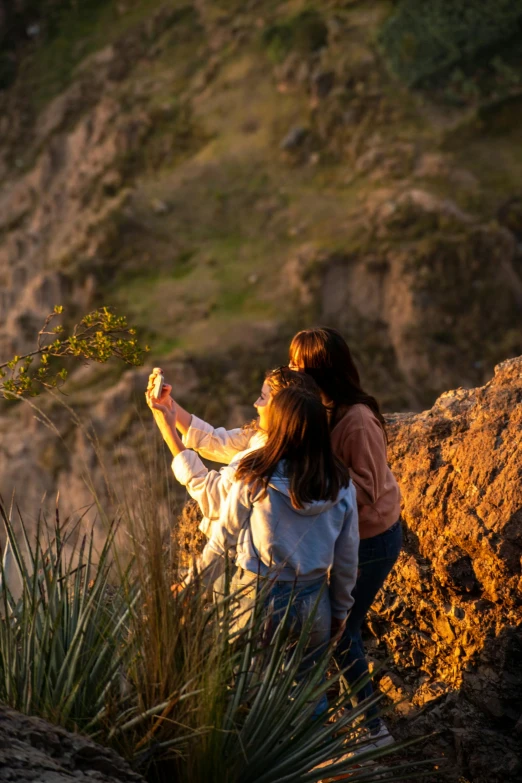 two women are holding onto some grass by a rock