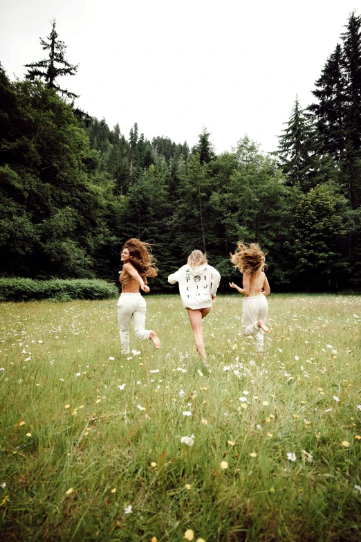 three girls running in the grass in a park