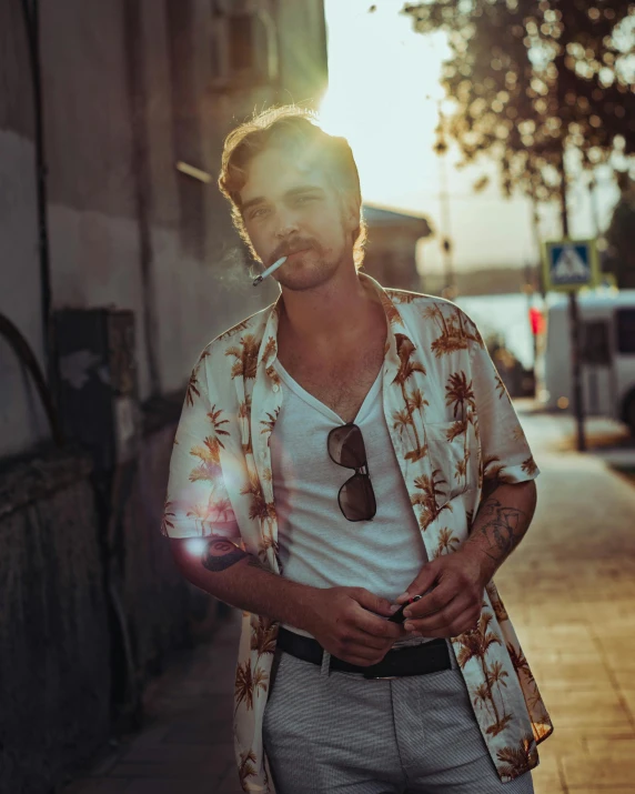 the man is wearing a flowered shirt smoking a cigarette