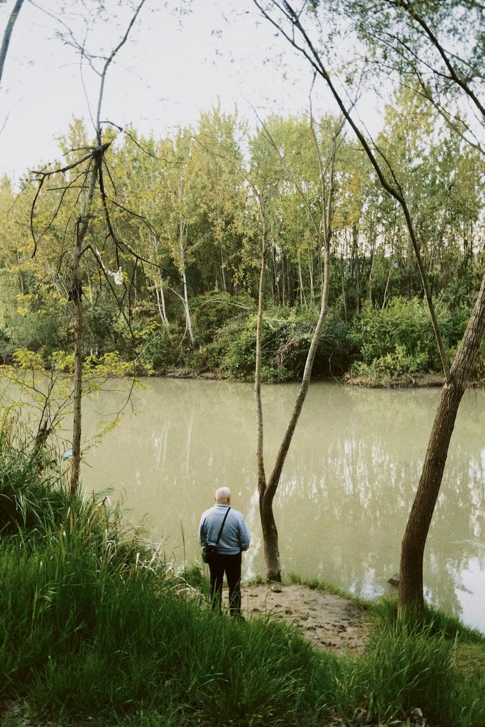 the older man is standing next to the pond