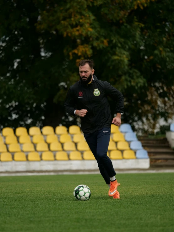 a bearded man runs on the grass while playing soccer