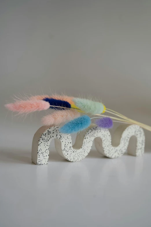 multicolored feathers on top of a letter spelling made from lace