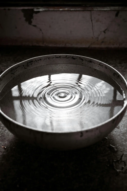 a small metal bowl on a cement surface