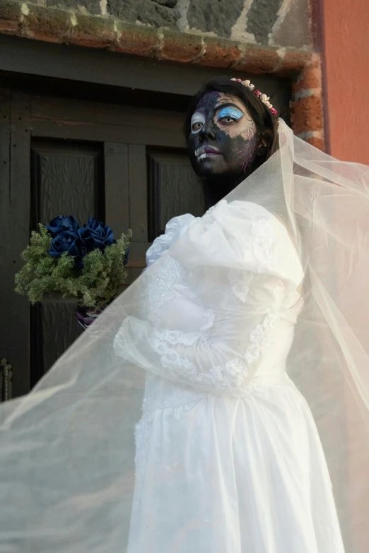 a woman in a white dress is wearing face paint