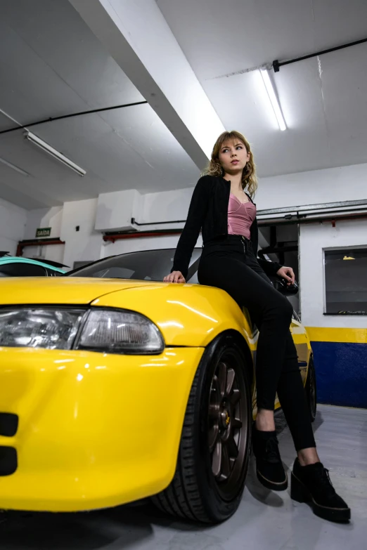 a woman sitting on top of a yellow sports car