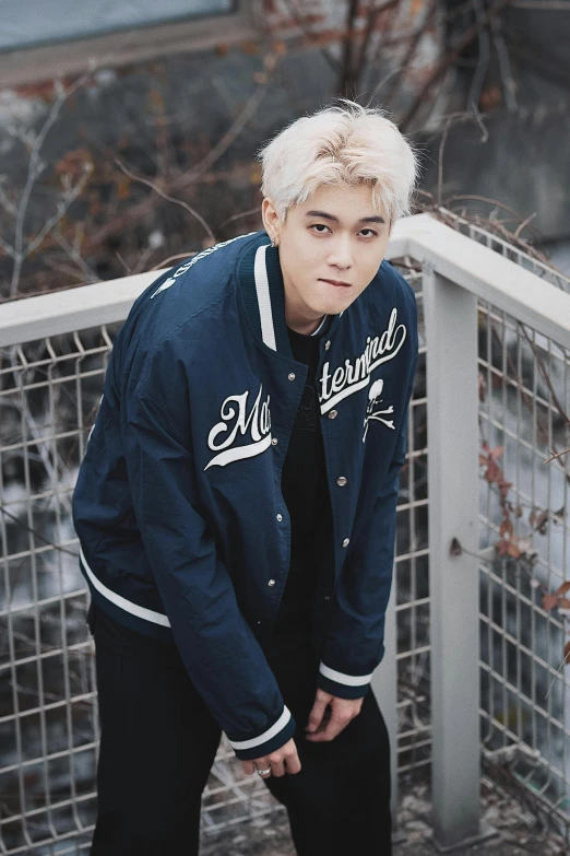 a man with white hair wearing a baseball jacket