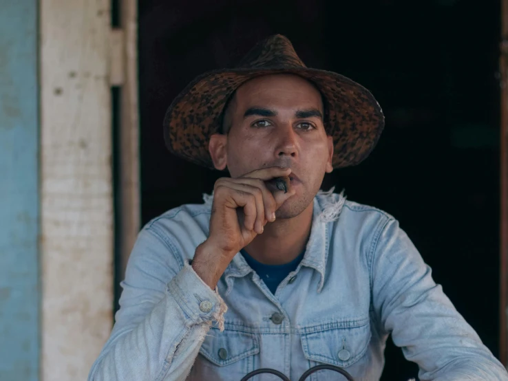 a man with a hat smoking a cigarette