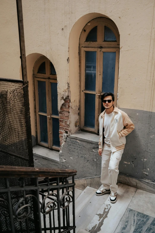 a man standing next to a building in a white suit