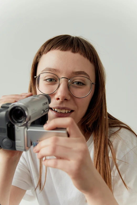 a girl in glasses is holding an object up