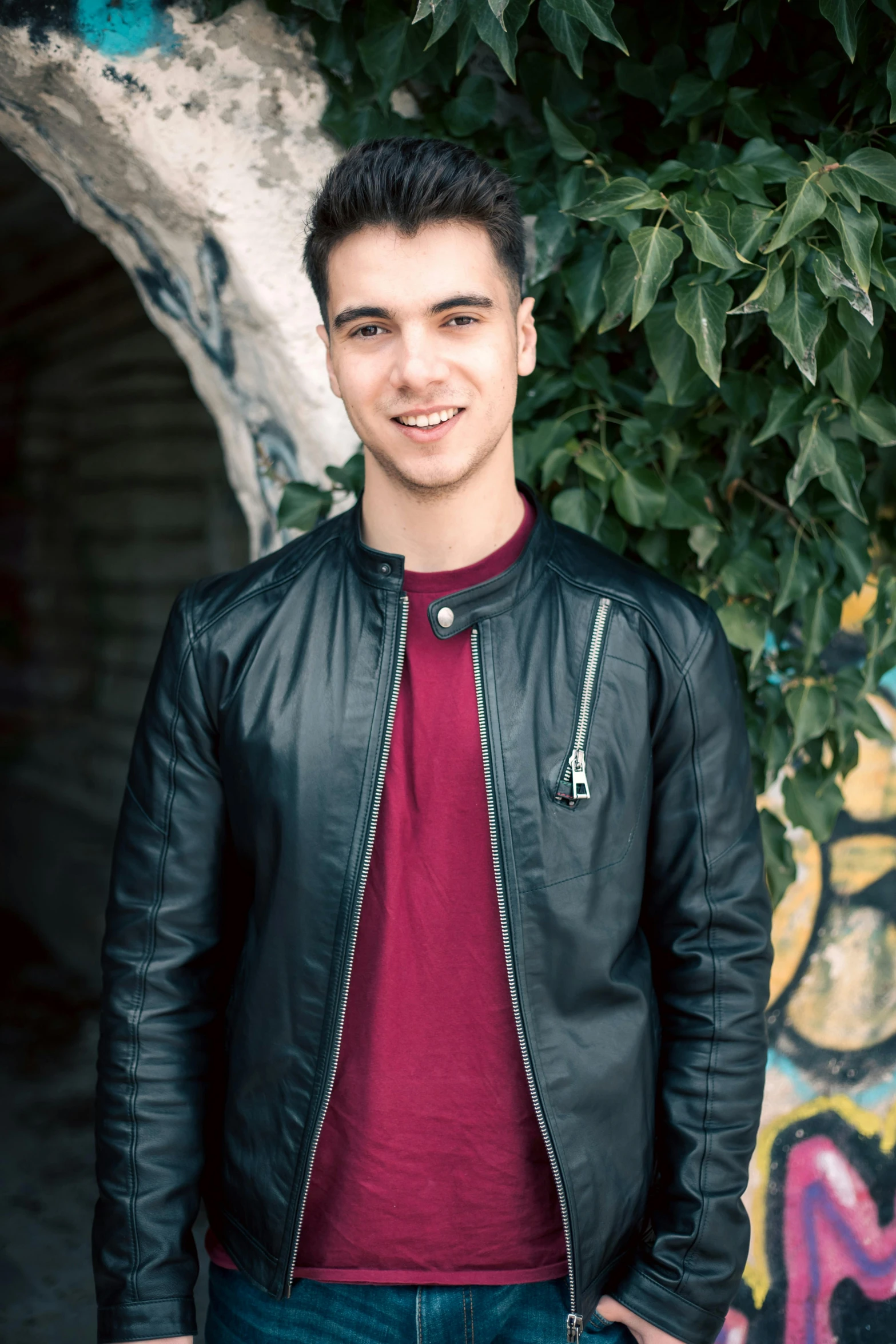 a man standing in front of some green bushes