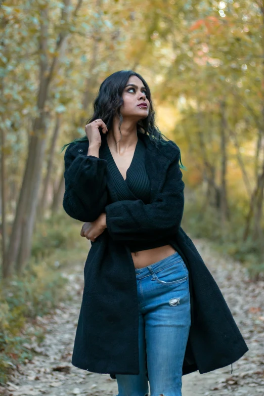 the young woman poses in front of a forest and tree