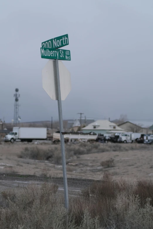 a green and white street sign with a truck in the background