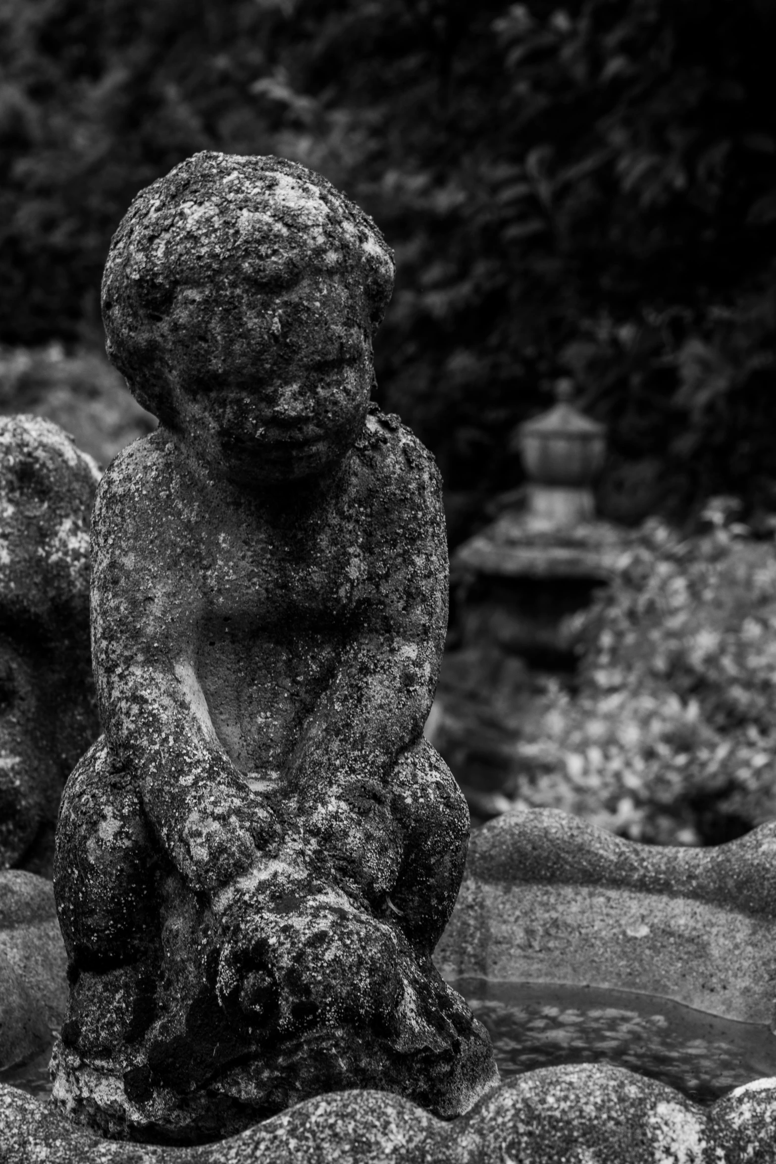 black and white pograph of a sculpture of a child sitting on rocks