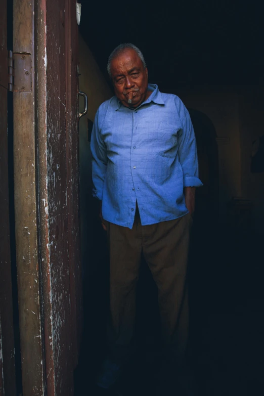 an old man standing in a doorway with his head turned