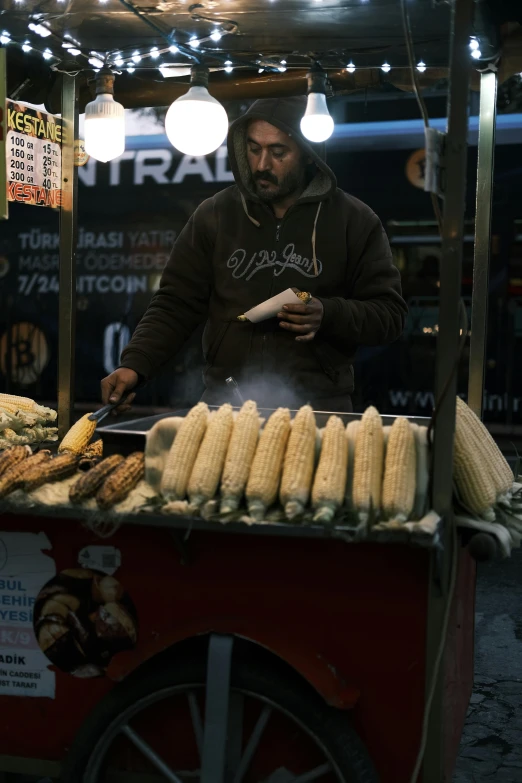 a man cooking corn on the cob in an open air market