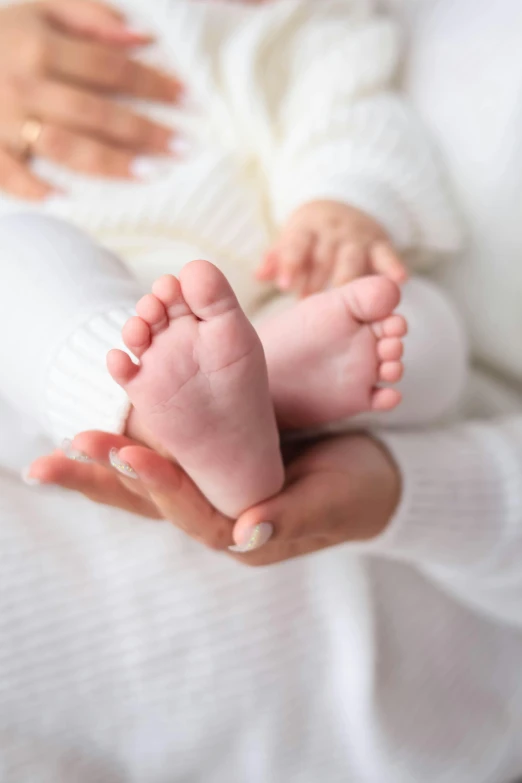 a newborn baby holding his parent hand while they are sleeping