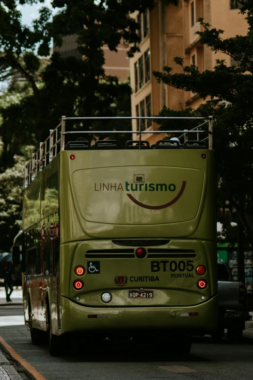 a green double decker bus drives down a street