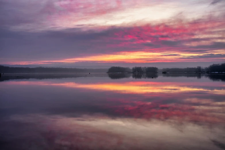 there is a large body of water at sunrise with clouds