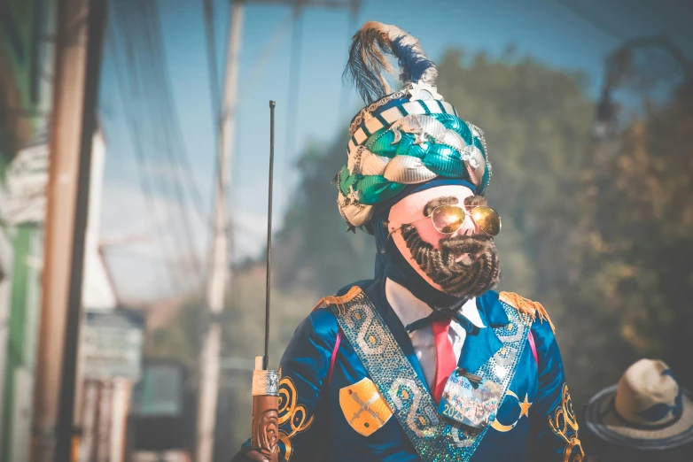 a man wearing elaborately decorated clothes and carrying a cell phone